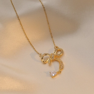 Elegant gold bow necklace with sparkling zircon and pear-shaped drop pendant on satin
