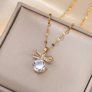 Elegant gold bow necklace featuring round zircon pendant on a silk jewelry gift box