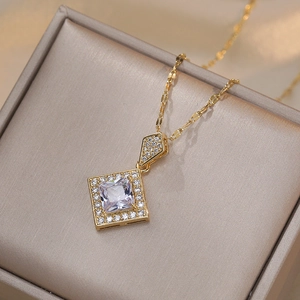 Elegant gold square necklace with clear zircon pendant on a jewelry box background