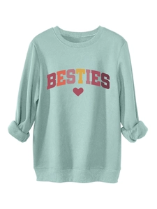 Close-up of mint green crewneck sweatshirt showing BESTIES lettering and heart detail