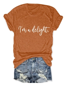 Flat lay of a burnt orange crew neck T-shirt with white text and ripped denim shorts