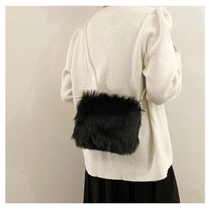 Sac bandoulière chic en fausse fourrure noire avec sangle en perles porté par le modèle