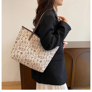 Side view of a large tote bag featuring brown letter prints and dark leather straps