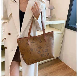 Detail of a brown leather tote bag with black letter prints and branded logo