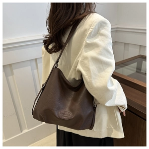 Detail of dark brown faux leather tote bag showing adjustable strap and embossed logo texture