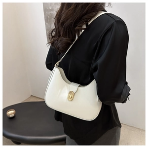 Detailed view of a white leather hobo bag with gold metal buckle worn by a model