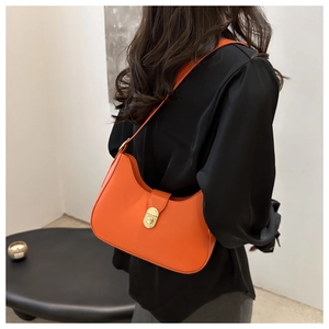 Orange semi-moon leather shoulder bag with gold circular twist lock on a stylish model