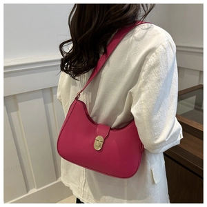 Close-up of rose pink saddle underarm bag with gold metal clasp on a female model