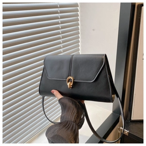 Close-up of minimalist black leather shoulder bag with elegant gold double-ring lock detail