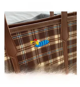 Detail of plaid tote bag featuring a cute dog embroidery and premium leather handle