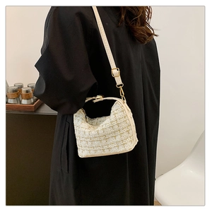Detail view of white tweed crossbody bag with gold hardware worn by model over black clothing