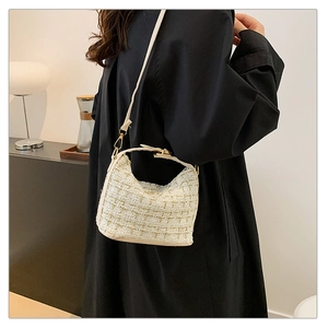 Cream tweed crescent shoulder bag with gold hardware shown on model in modern setting