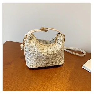 Close-up of off-white tweed texture and gold hardware on the elegant versatile handbag