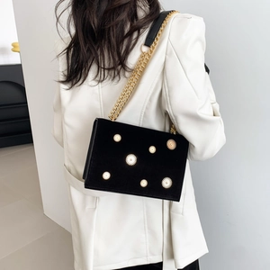 Fashionable black velvet tote with gold sunburst metal studs and chain strap