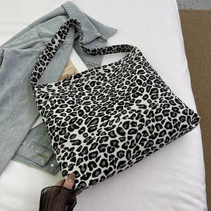Detail of large leopard print canvas tote bag with wide shoulder strap on casual denim