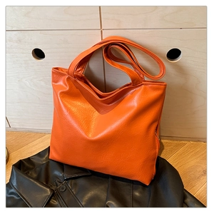 Close-up of vibrant orange PU leather tote bag showing fine texture and zipper detail