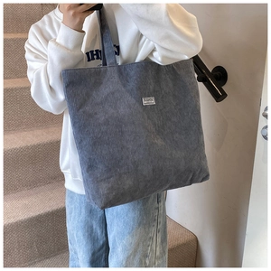Dettaglio della borsa tote in velluto a coste grigio con trama e etichetta Fashion