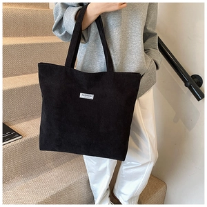 Dettaglio della borsa tote in velluto nero che mostra l'etichetta moda in un contesto reale