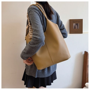 Detail view of khaki leather tote bag with silk scarf on handle for daily commute