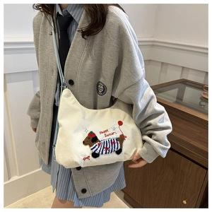 Detailed view of white corduroy tote bag featuring an embroidered dachshund puppy design