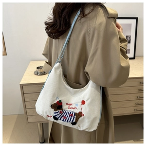 Detail of white corduroy shoulder bag with blue strap and cartoon dog embroidery
