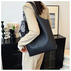 Detail of black pebbled faux leather tote bag with decorative black and white checkered scarf