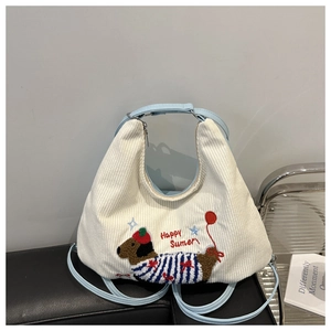 Detail of white corduroy tote featuring a dachshund embroidery and blue shoulder strap