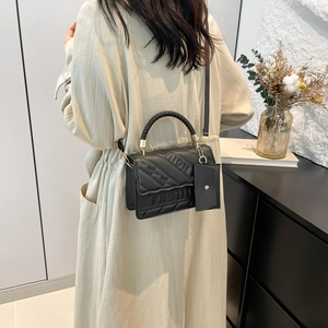 Black quilted crossbody bag with woven handle and small coin purse in a lifestyle setting
