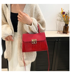 Detail view of red crocodile-pattern handbag with elegant gold square lock hardware