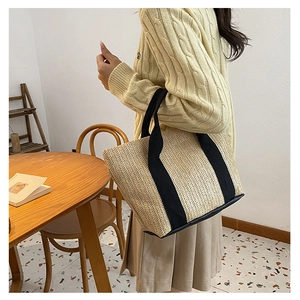 Straw tote bag with black canvas straps and reinforced bottom for summer travel