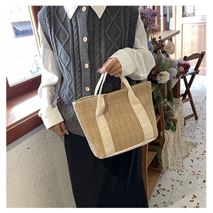Detail of woven straw tote bag with cream cotton handles in a lifestyle setting