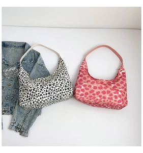 Dettaglio di borse hobo con stampa leopardata e macchie rosa su una giacca di jeans blu