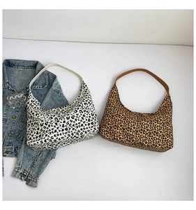 Dettaglio di borse hobo in tela leopardata beige e marrone accanto a una giacca di jeans