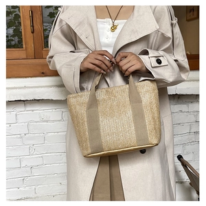 Detailed shot of a woven straw tote bag with fabric handles and gold base accent