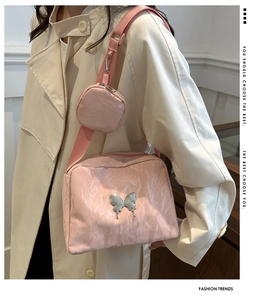 Detail of pink crossbody bag with pleated texture and silver butterfly metal charm