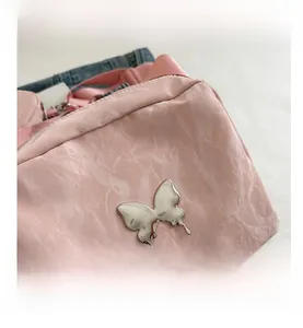 Close-up of pink pleated fabric with silver butterfly metallic charm on shoulder bag