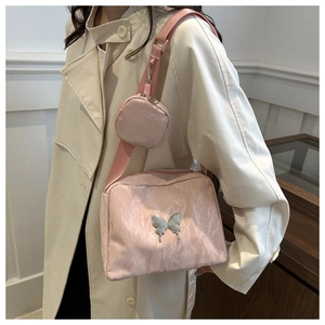 Detail of pink two-in-one crossbody bag with silver butterfly charm and mini coin purse
