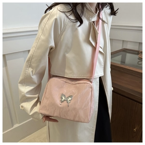 Detail of light pink crossbody bag with silver butterfly ornament and adjustable strap