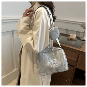 Detail of silver pleated shoulder bag with butterfly metal buckle and mini coin purse charm