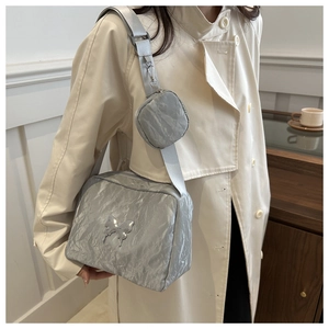 Detail of silver metallic nylon crossbody bag with butterfly accessory and round coin purse