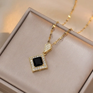 Elegant gold titanium necklace with square black zircon pendant on champagne silk background