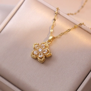 Macro detail of golden flower pendant with pear-cut zircon on soft beige jewelry box