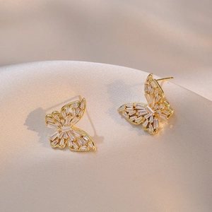Elegant gold butterfly earrings with cubic zirconia stones on light silk fabric background