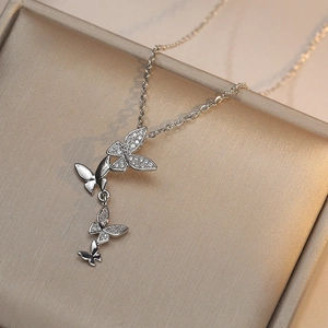 Collier papillon argenté avec quatre pendentifs en zircone sur un coffret à bijoux
