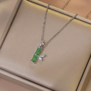 Collier avec pendentif bambou en œil-de-chat vert et zircon sur une boîte à bijoux dorée