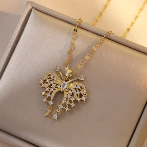 Golden butterfly necklace with zircon pavé and teardrop charms on a champagne jewelry box