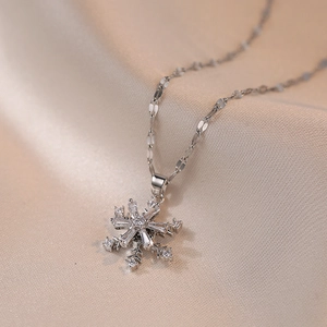 Elegante rotierende Schneeflocke Halskette mit Zirkonia auf Seidenstoff Hintergrund