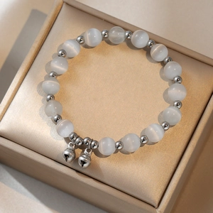 Elegant cat eye stone beaded bracelet with silver bells on a jewelry box background