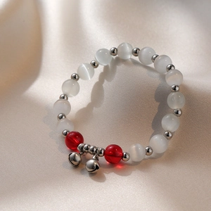 Bracelet élégant en pierre œil de chat avec grelots argentés sur fond de soie beige