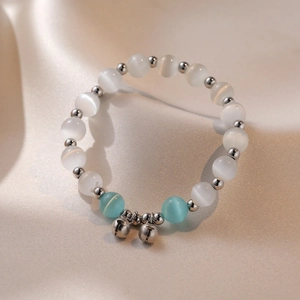 Close-up of cat eye stone beaded bracelet featuring silver bells and blue accent beads